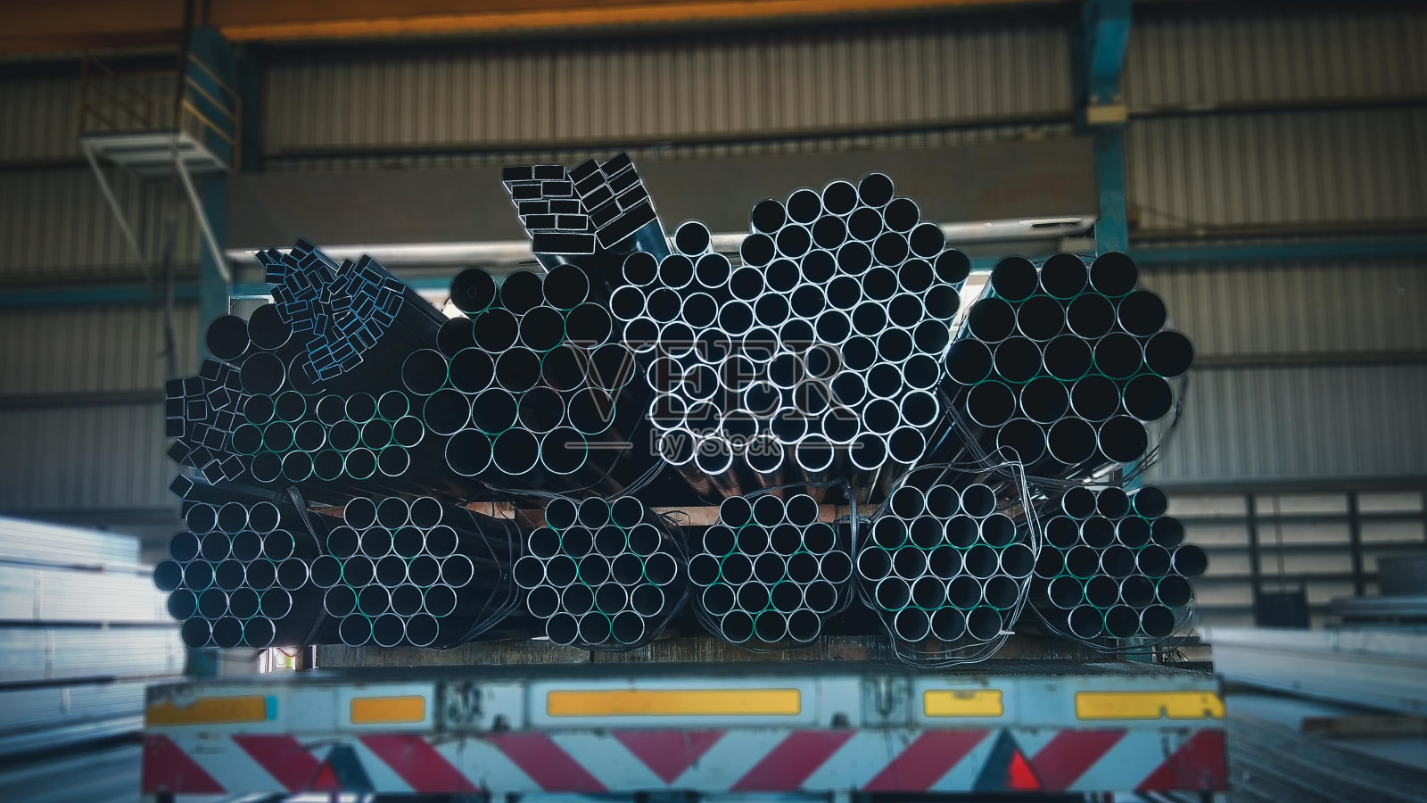 堆叠的钢管与建筑钢材，黑色管道，金属管，特写单色照片与选择性聚焦，堆叠的许多管道在建筑工地照片摄影图片