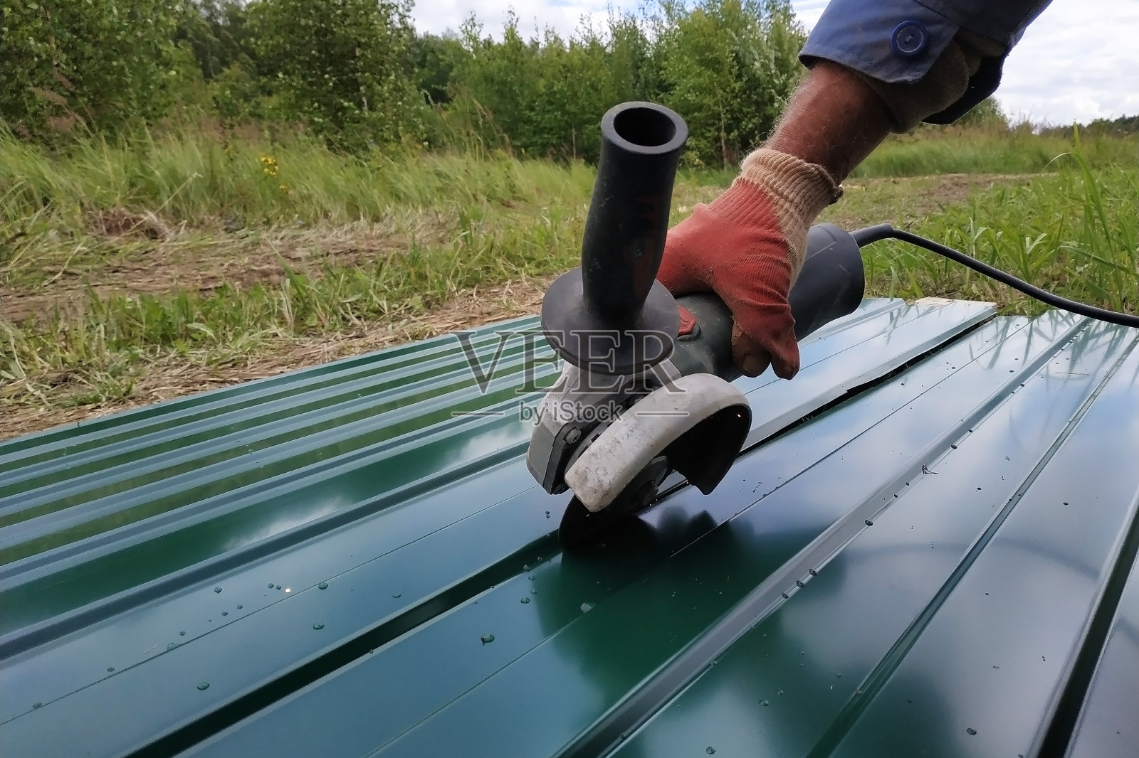 村民在户外用角磨机切割金属片。照片摄影图片