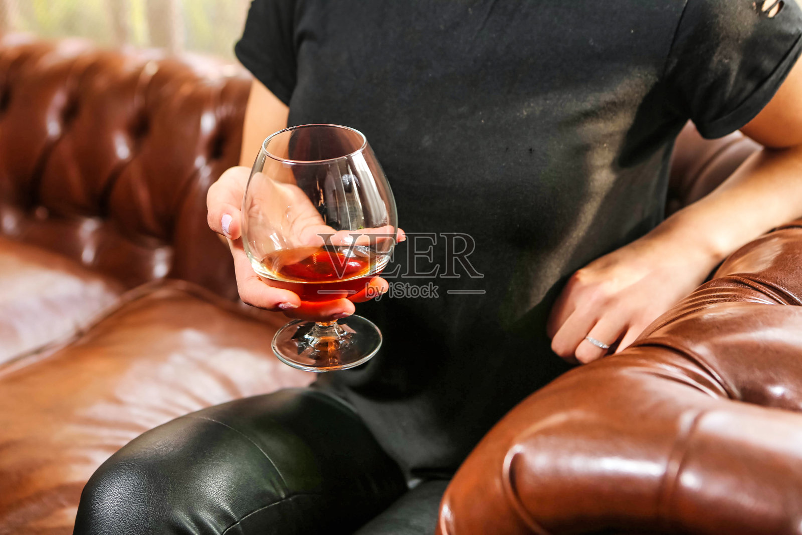 一个人坐在沙发上拿着一杯酒照片摄影图片