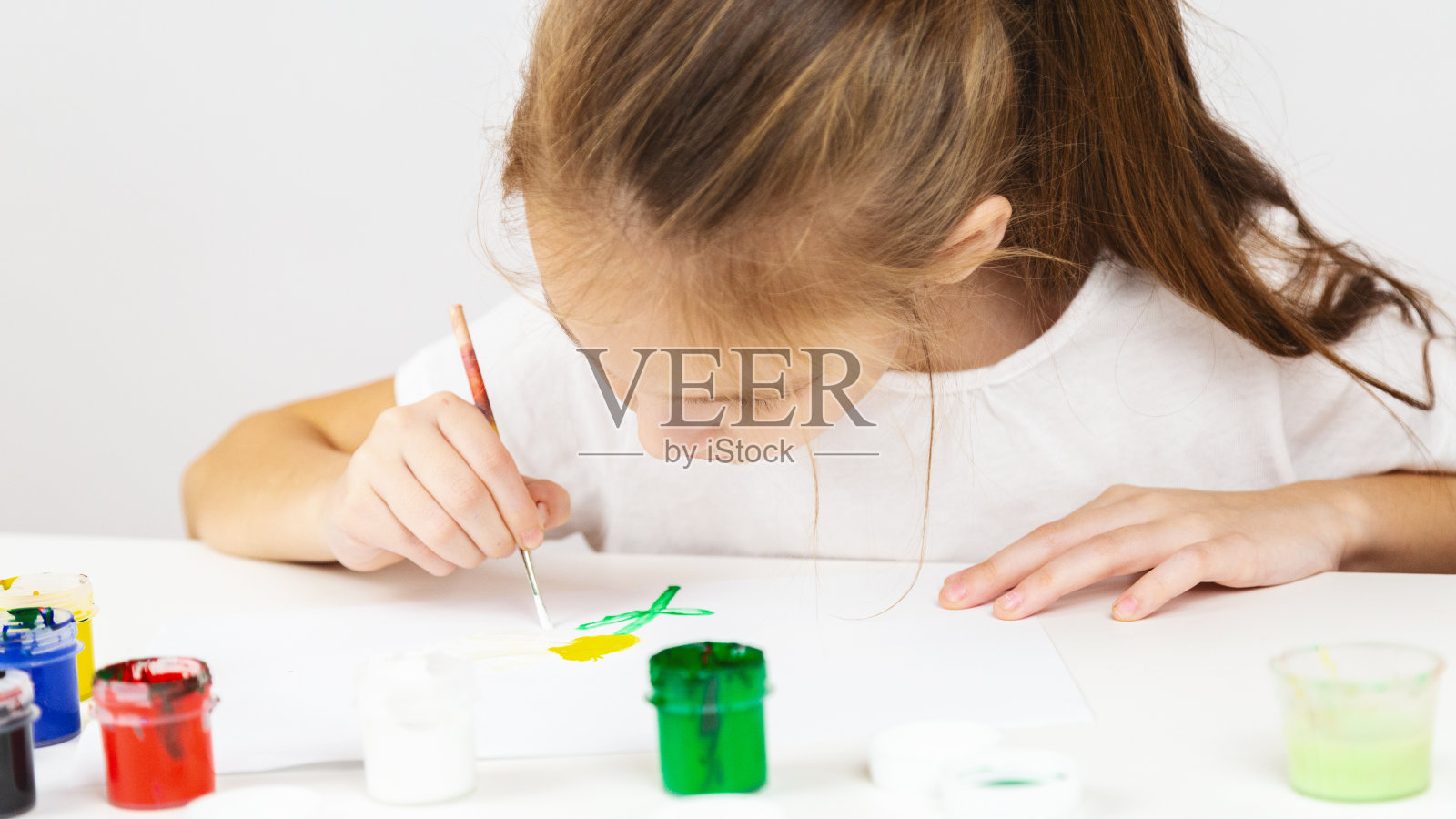 一个女孩的肖像，在美术课上画在桌子上在室内，额外的绘画课程。照片摄影图片