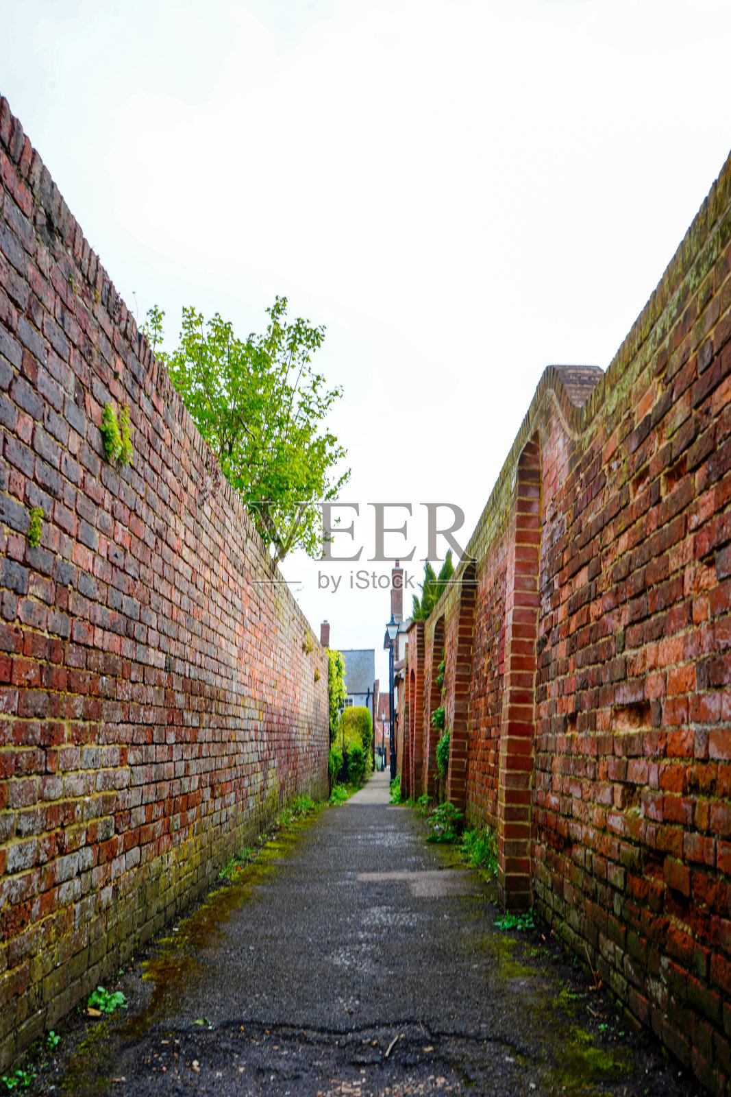 镇上两堵红砖墙之间的狭窄小路照片摄影图片