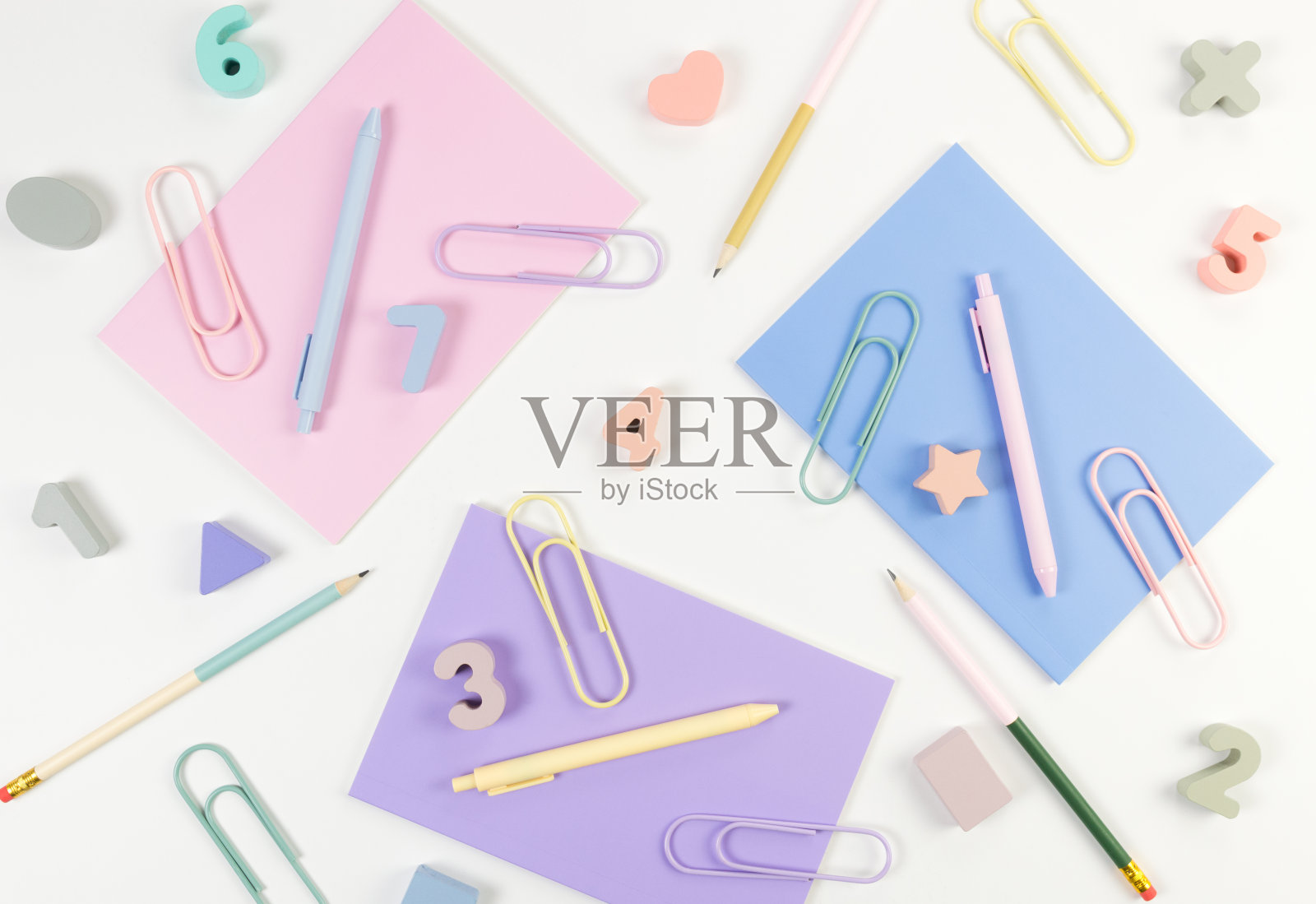 白色背景上的粉色、紫色和蓝色笔记本的俯视图。彩色钢笔，铅笔，回形针，数字，形状和别针。学校、办公室的墙纸。照片摄影图片