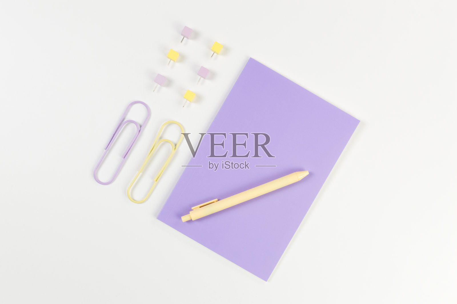白色背景上的紫色笔记本的顶视图。回形针、笔和别针。学校、办公室的墙纸。照片摄影图片