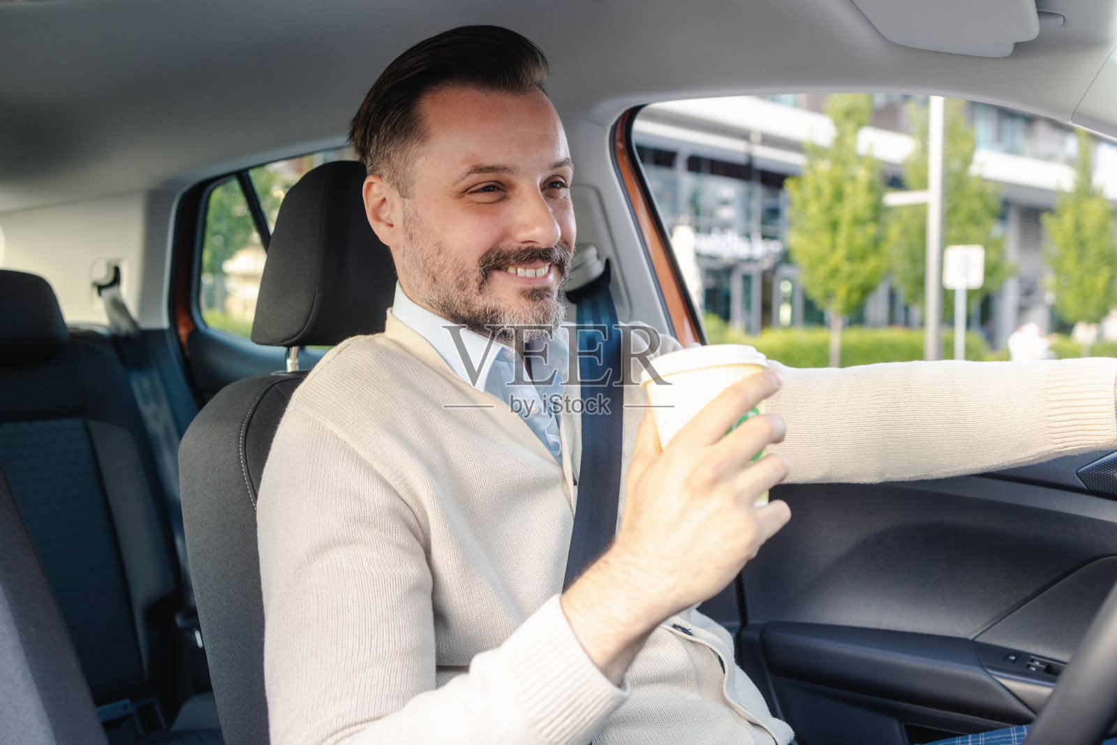 男司机喝着早晨的咖啡，在城市里开车照片摄影图片