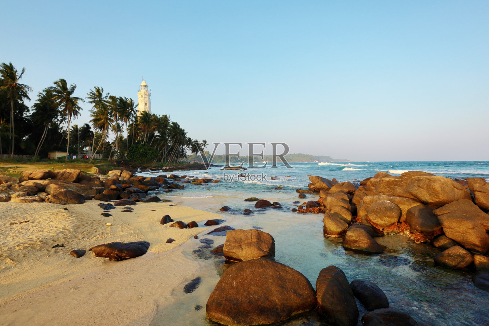 白色灯塔附近的热带岩石沙滩。唐德拉角灯塔是斯里兰卡海边的著名地标照片摄影图片