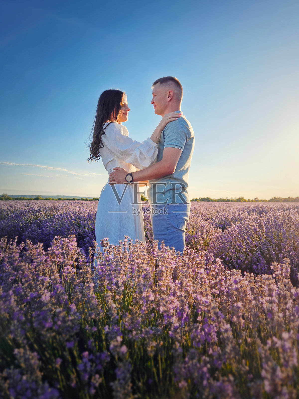 一对年轻的情侣在薰衣草地里约会时拥抱在一起。如画的夏日风光，爱与浪漫的概念照片摄影图片