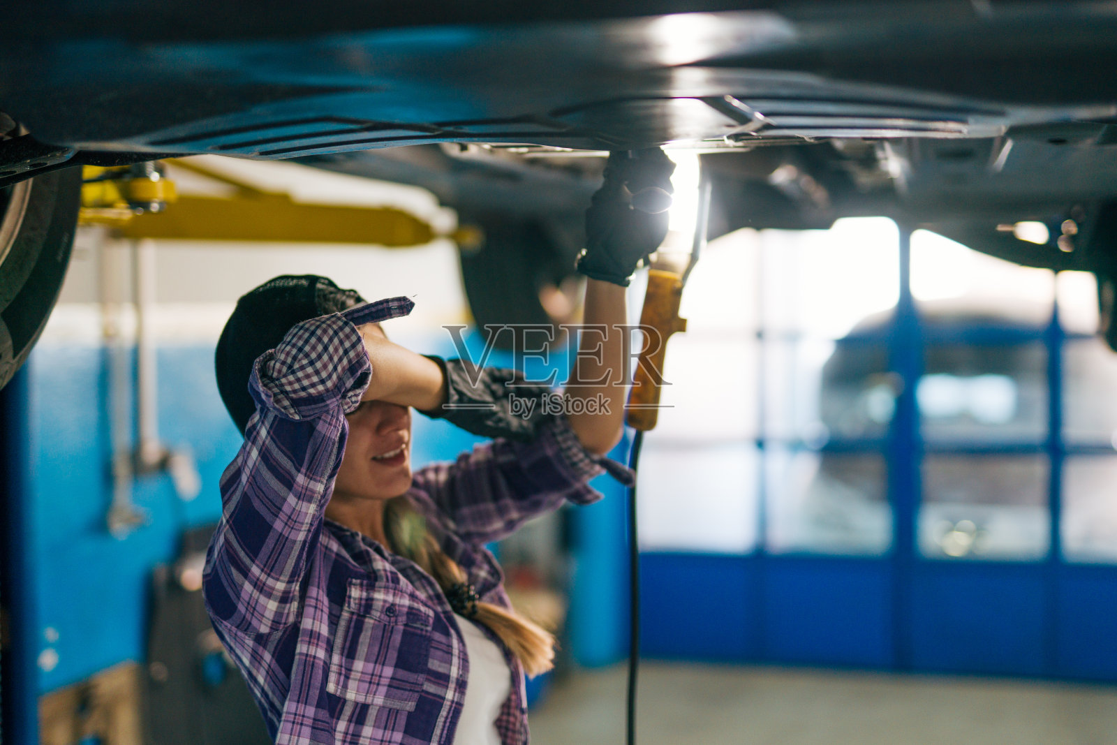 在汽车修理店修车的妇女照片摄影图片