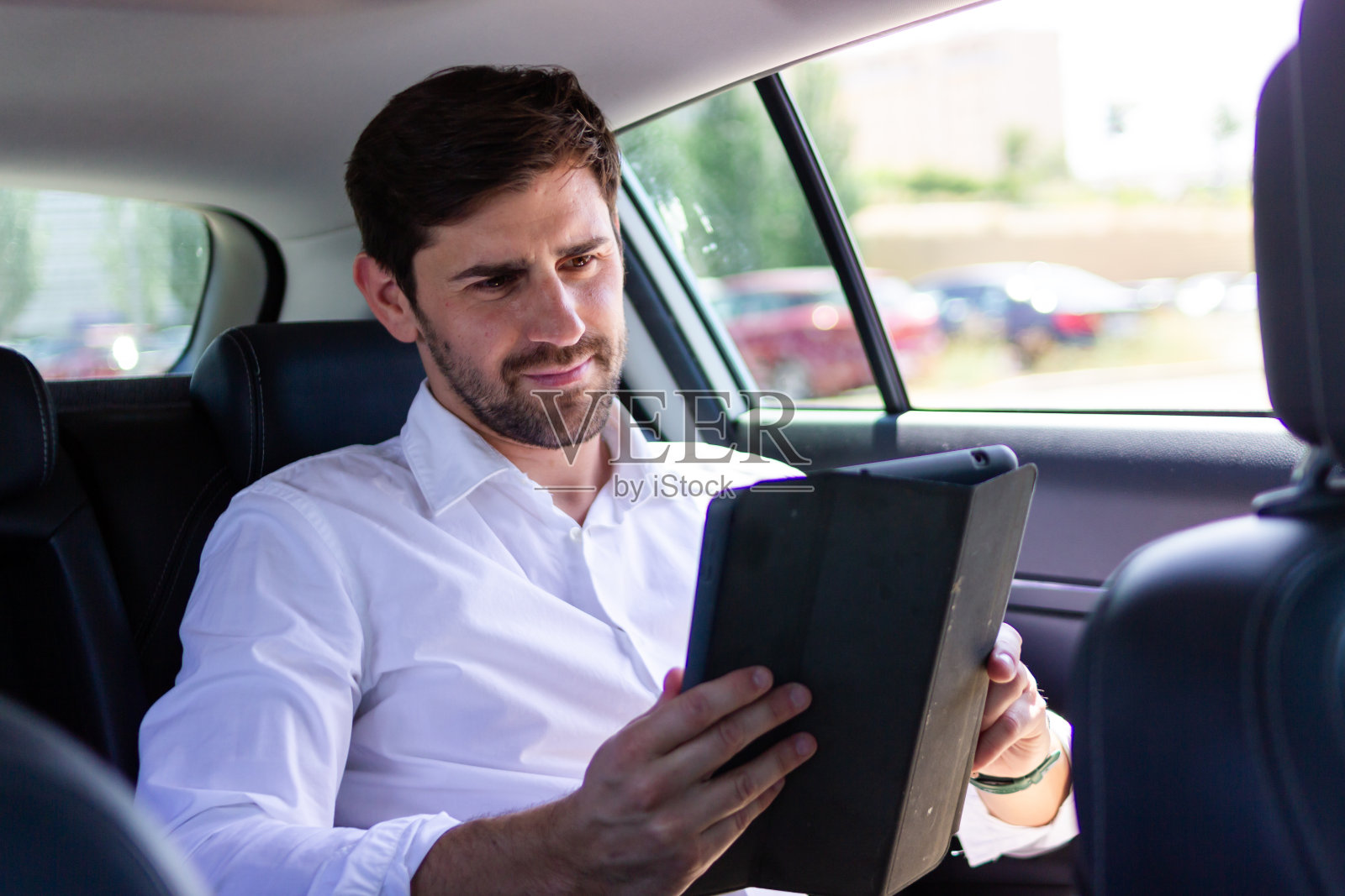 商人坐在汽车后座上摆弄平板电脑照片摄影图片