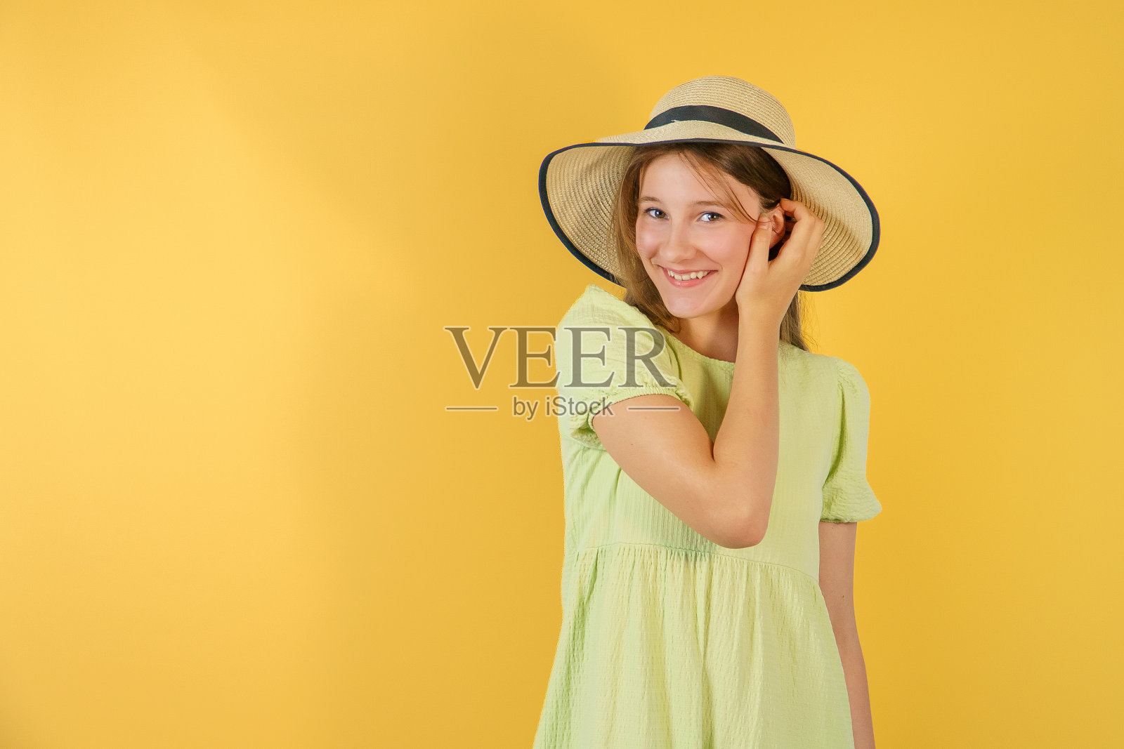 快乐的童年。开朗的小女孩戴着草帽。孩子们的海滩时尚。黄色背景上的小孩。节日的欢乐和活动。满心欢喜。期待已久的暑假照片摄影图片