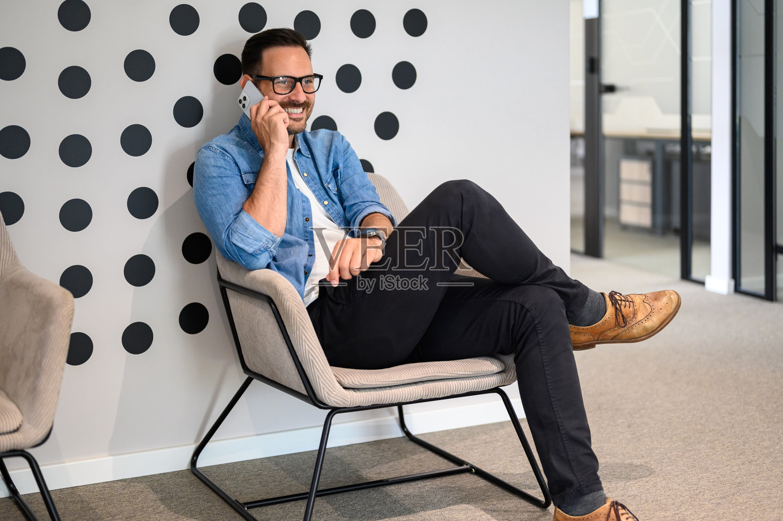 男工程师坐在办公室的椅子上微笑着讨论电话照片摄影图片
