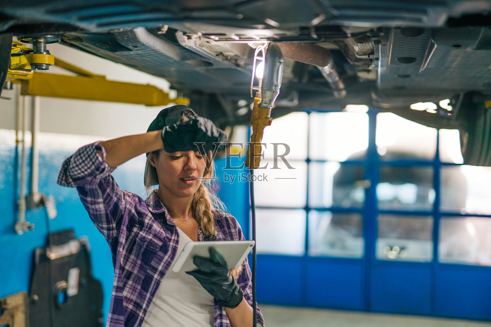 一名女机械师在一家汽车修理店工作时手持数码平板电脑的照片照片摄影图片