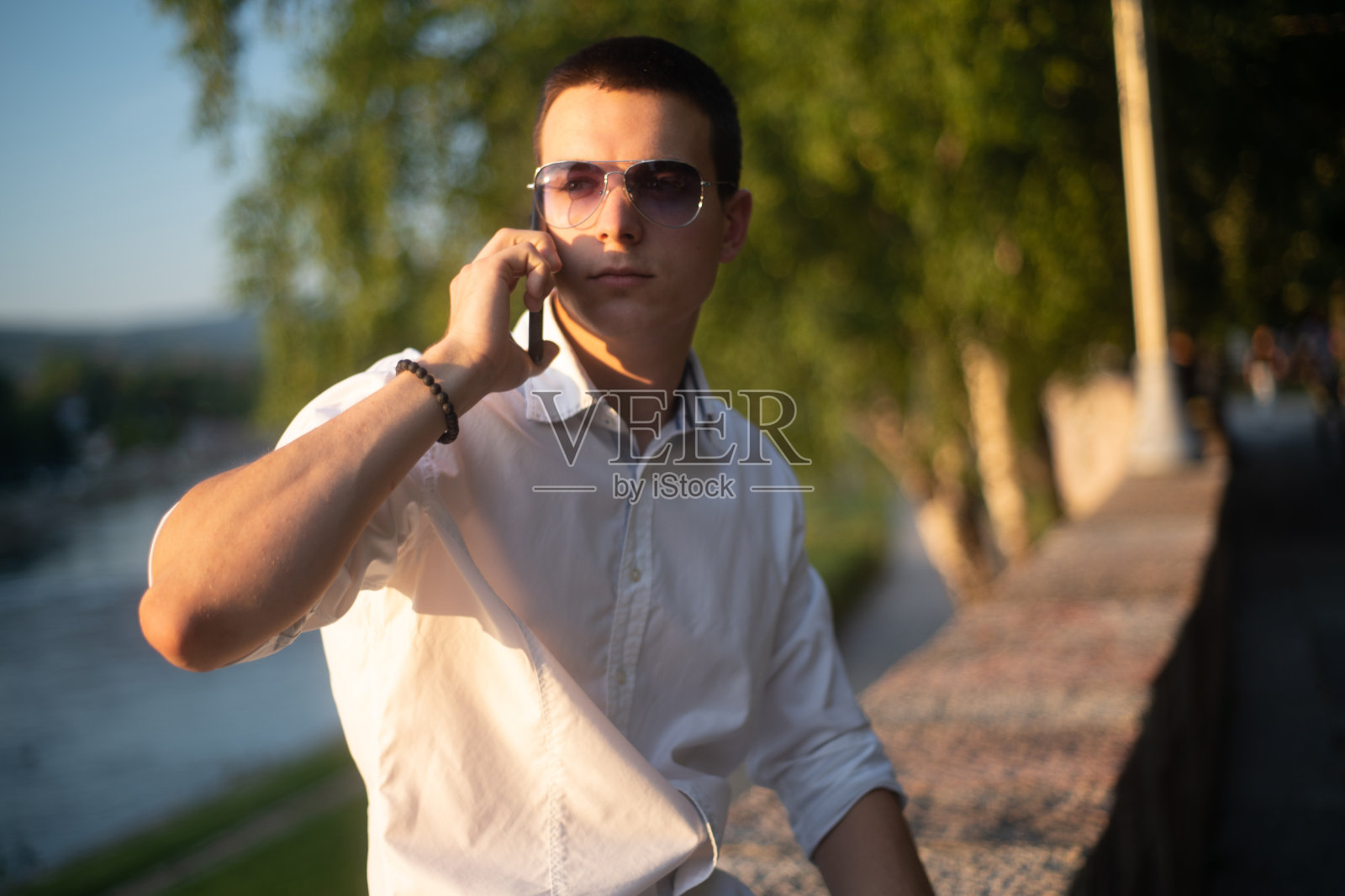 戴着墨镜的年轻人在城市河堤边打电话照片摄影图片