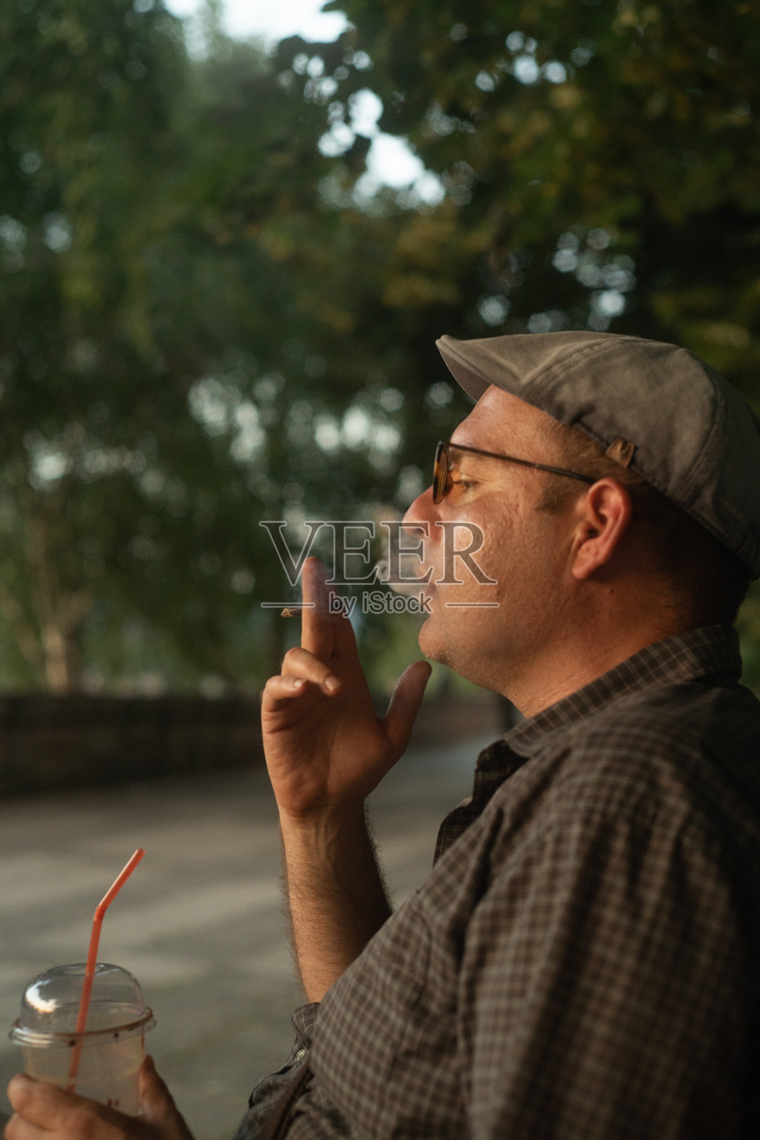 在公园里抽烟喝咖啡的帅哥照片摄影图片