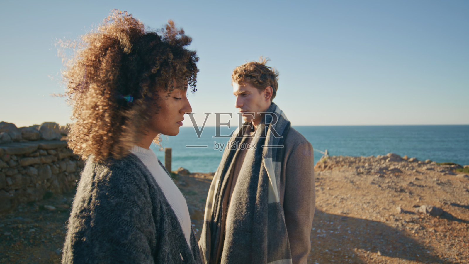 悲伤的夫妇在海边悬崖摆特写。卷发女人金发男人感到不安照片摄影图片