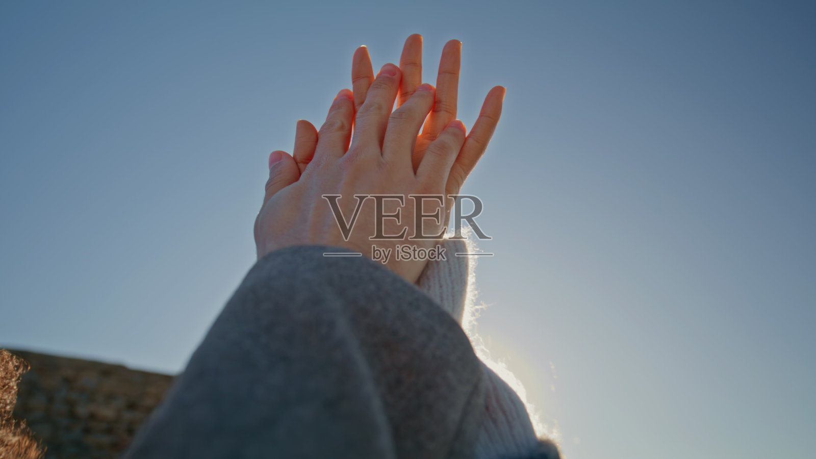 约会的恋人交叉手指在天空背景特写。情侣手心相碰照片摄影图片