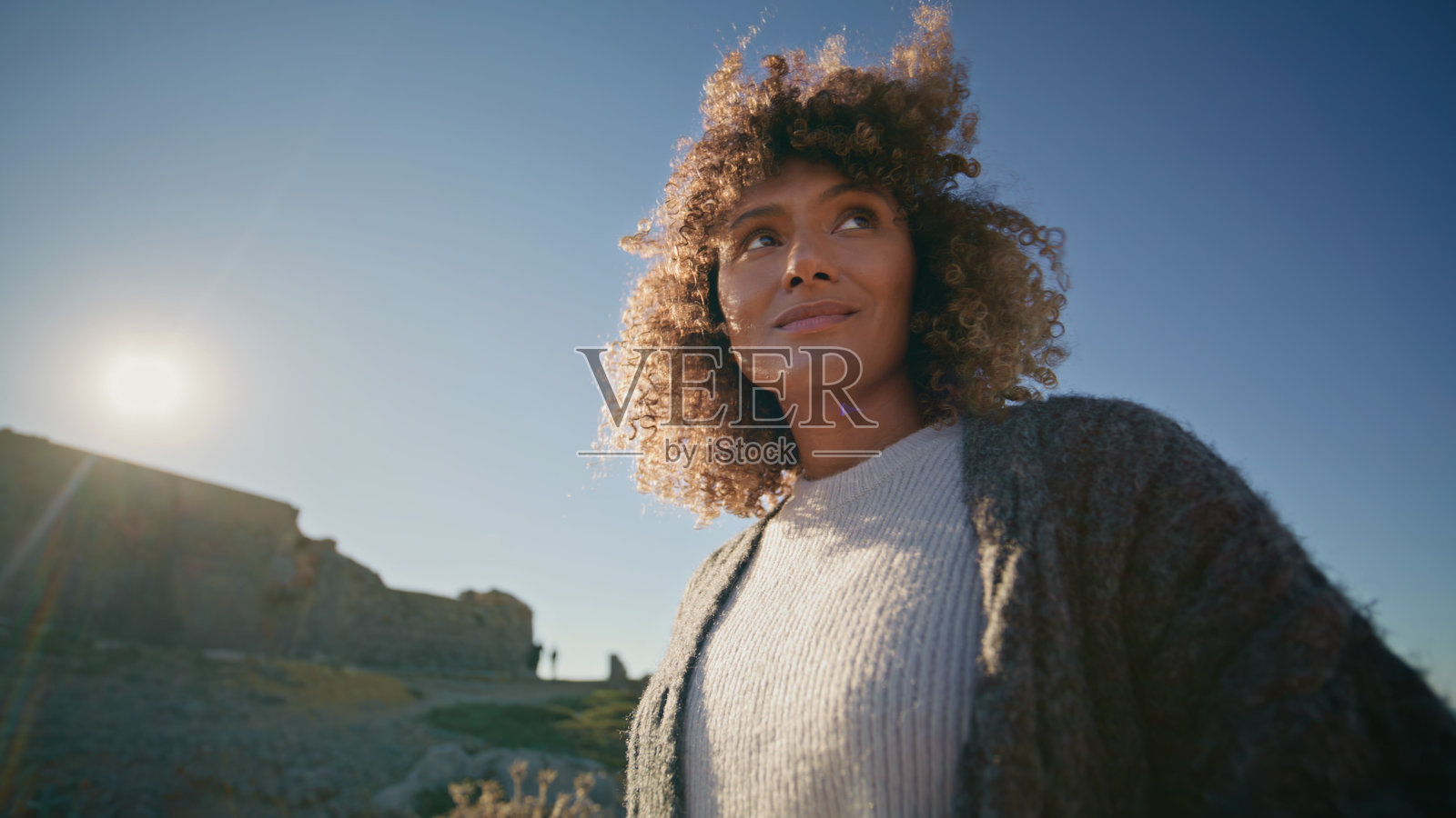 走路的女孩看着远处的蓝天背景特写。快乐的女人摆姿势照片摄影图片