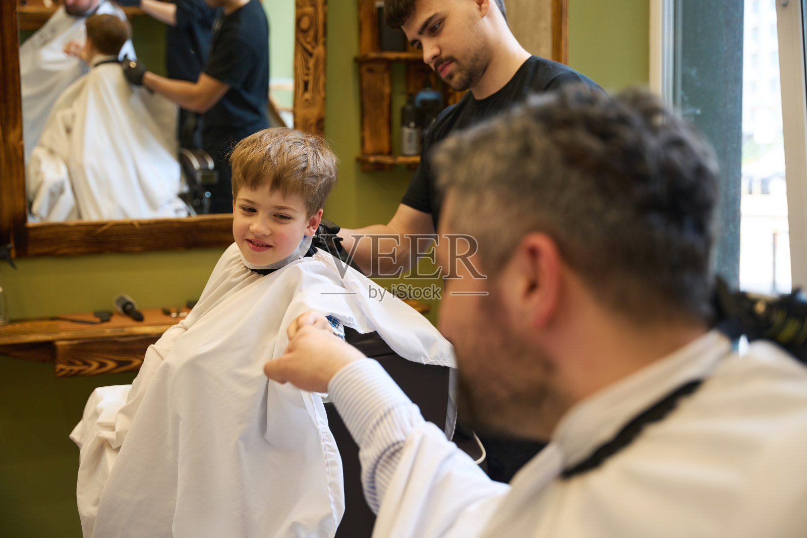 父亲扶着刚来理发店的受惊的儿子照片摄影图片
