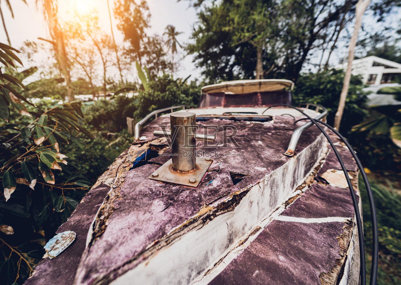 在热带森林环绕的垃圾填埋场上，旧而生锈的摩托艇照片摄影图片
