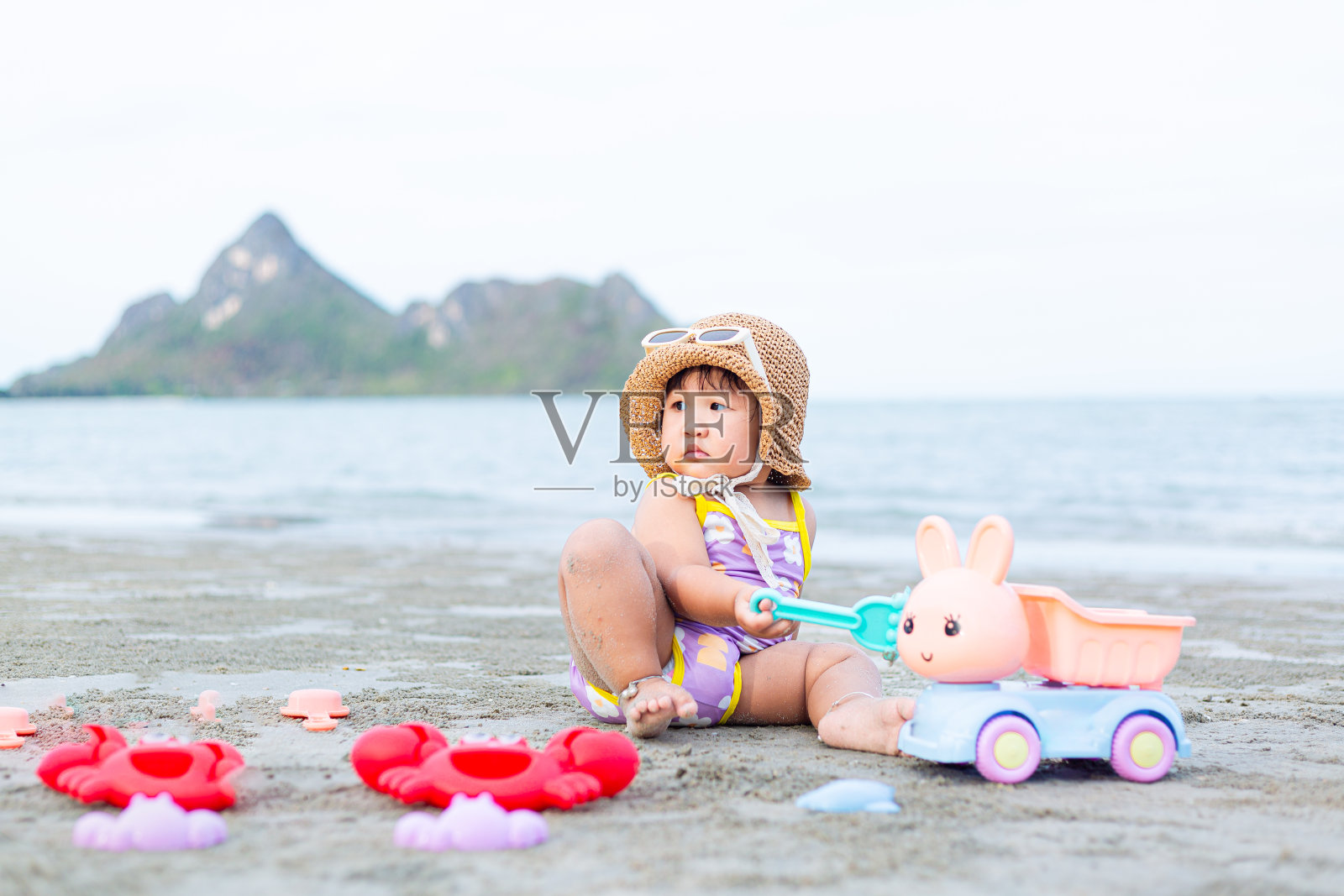 度假的小女孩在沙滩上玩沙子，可爱的小女孩在热带海滩上玩沙子照片摄影图片