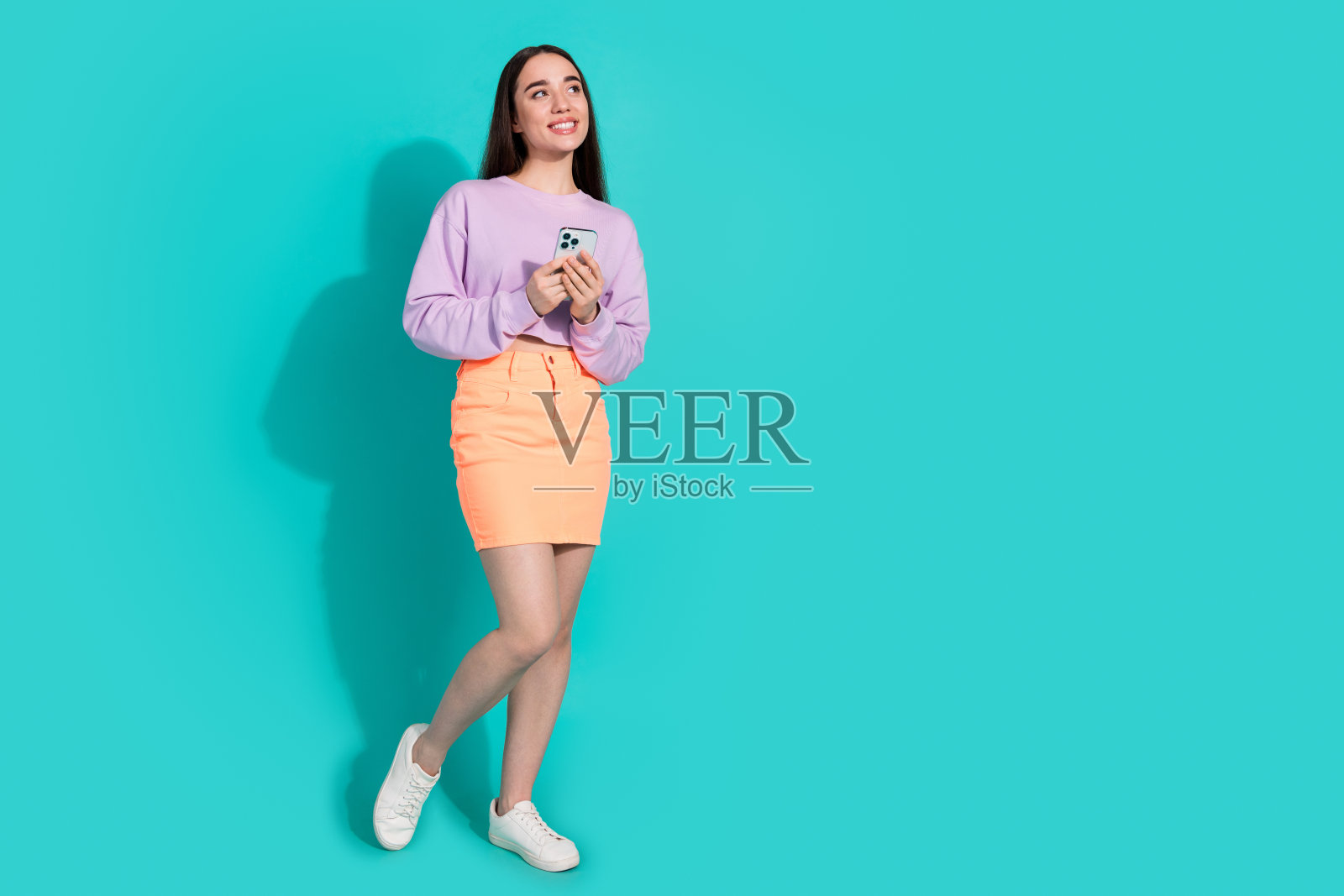 可爱的年轻女士的全身照片看起来空空如也，手持装置穿着时髦的紫色衣服，孤立在海蓝宝石的背景上照片摄影图片