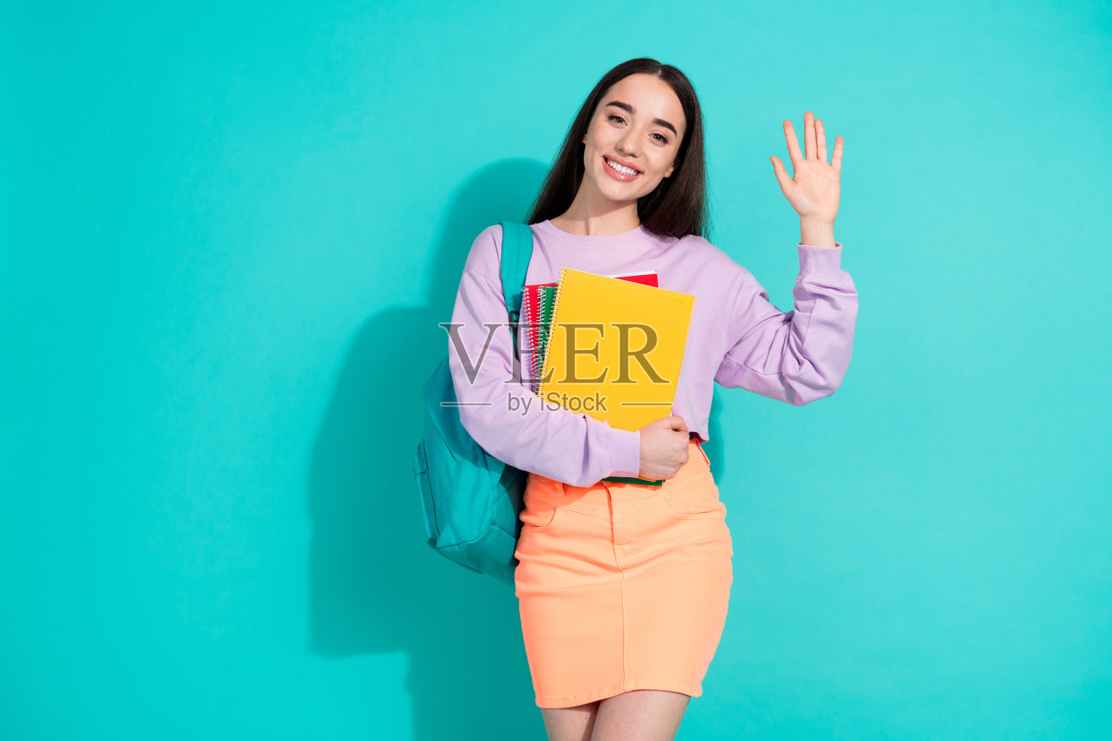 可爱的年轻女士的照片肖像拿着抄写本挥手穿着时尚的紫色服装孤立的海蓝宝石色背景照片摄影图片