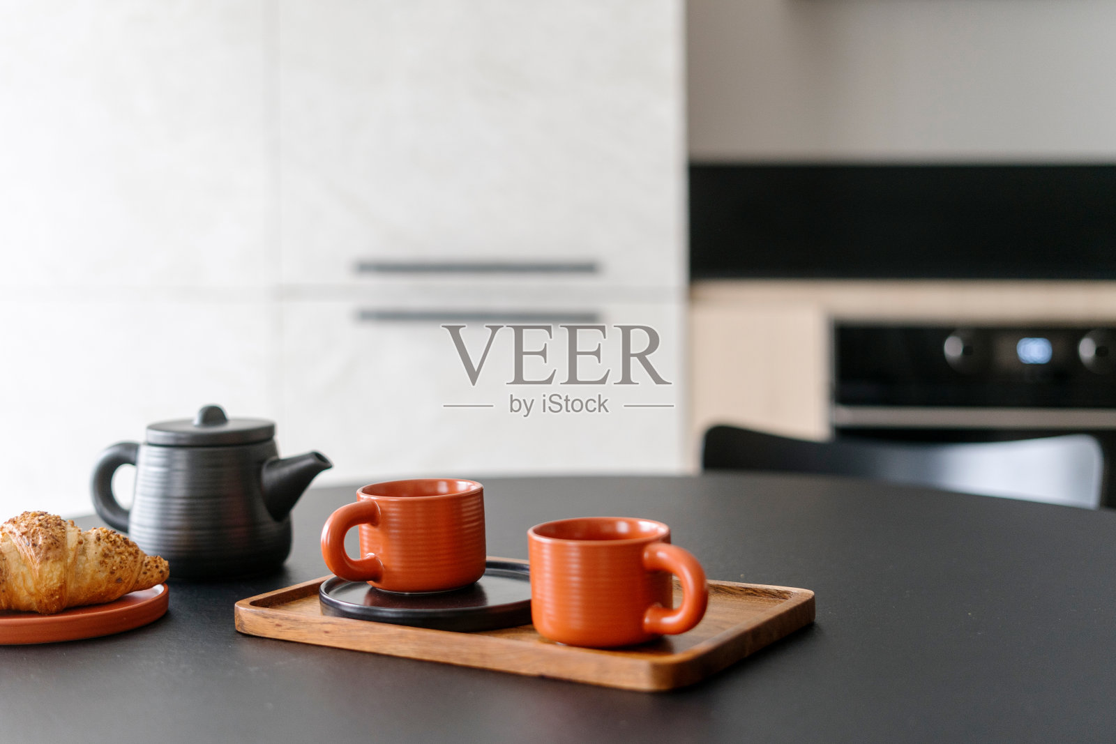 有选择的重点放在竹板上的杯子、茶壶和盘子上，桌子上有面包照片摄影图片