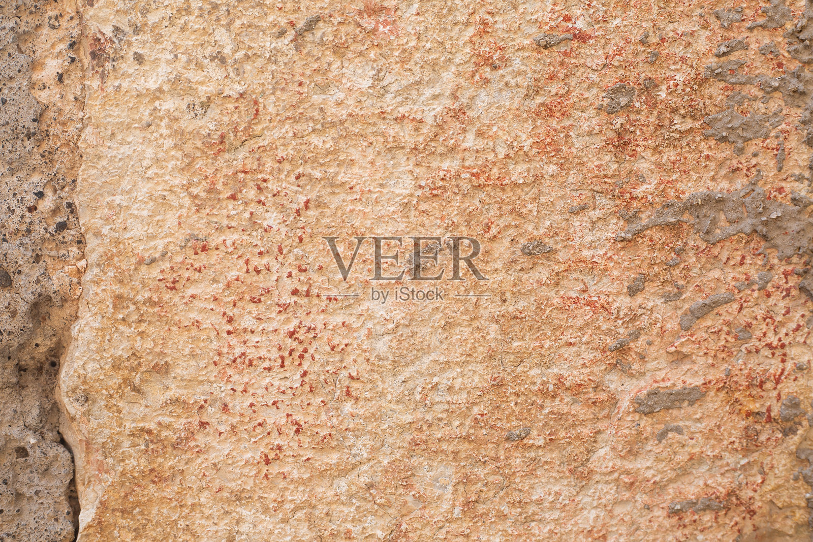 米黄色和橙色的大石块砌成的墙壁，上面有水泥和红色的油漆点。背景和壁纸纹理图片。副本的空间。天然建筑材料。砂岩的建筑。照片摄影图片