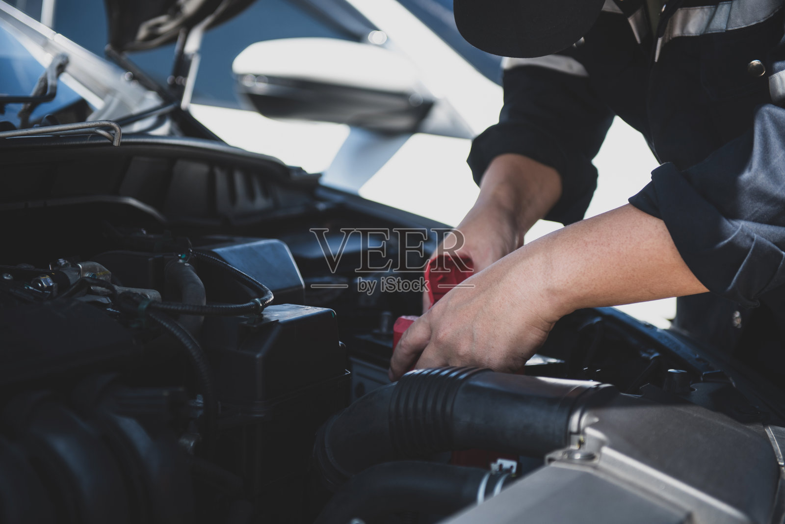 汽车修理工修理汽车他正在从盒子里取出汽车电池，因为电池没电了，必须更换。照片摄影图片