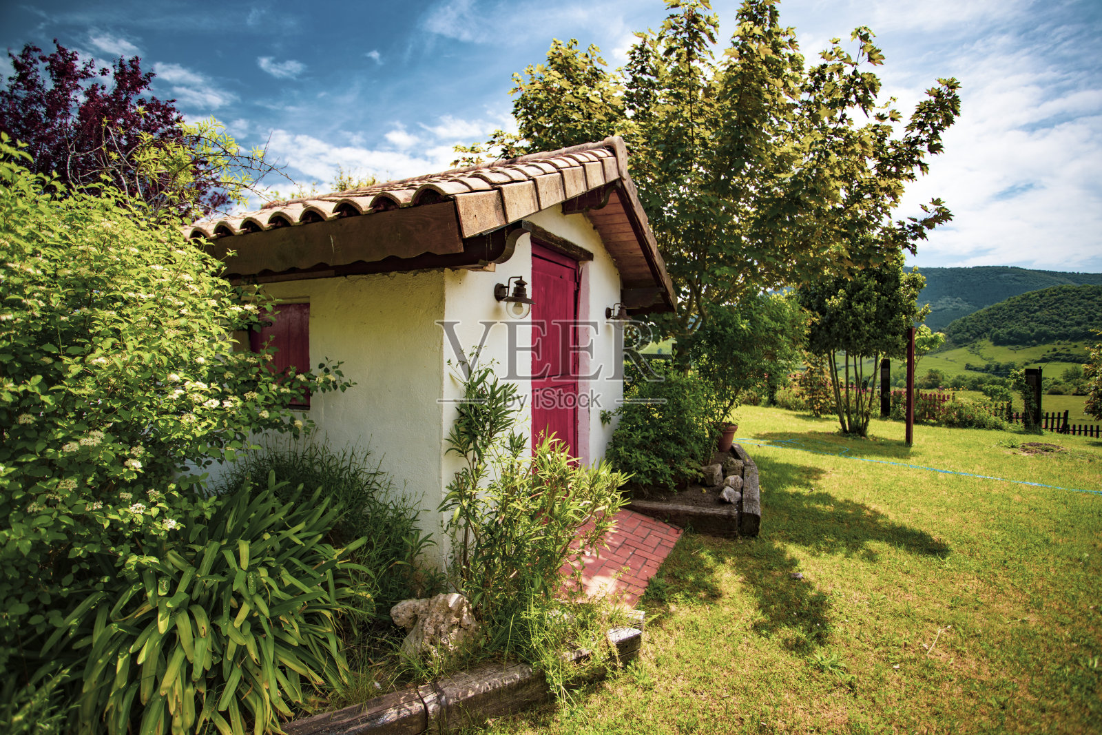 童话般的可爱小屋，周围环绕着树木、植物和鲜花。照片摄影图片