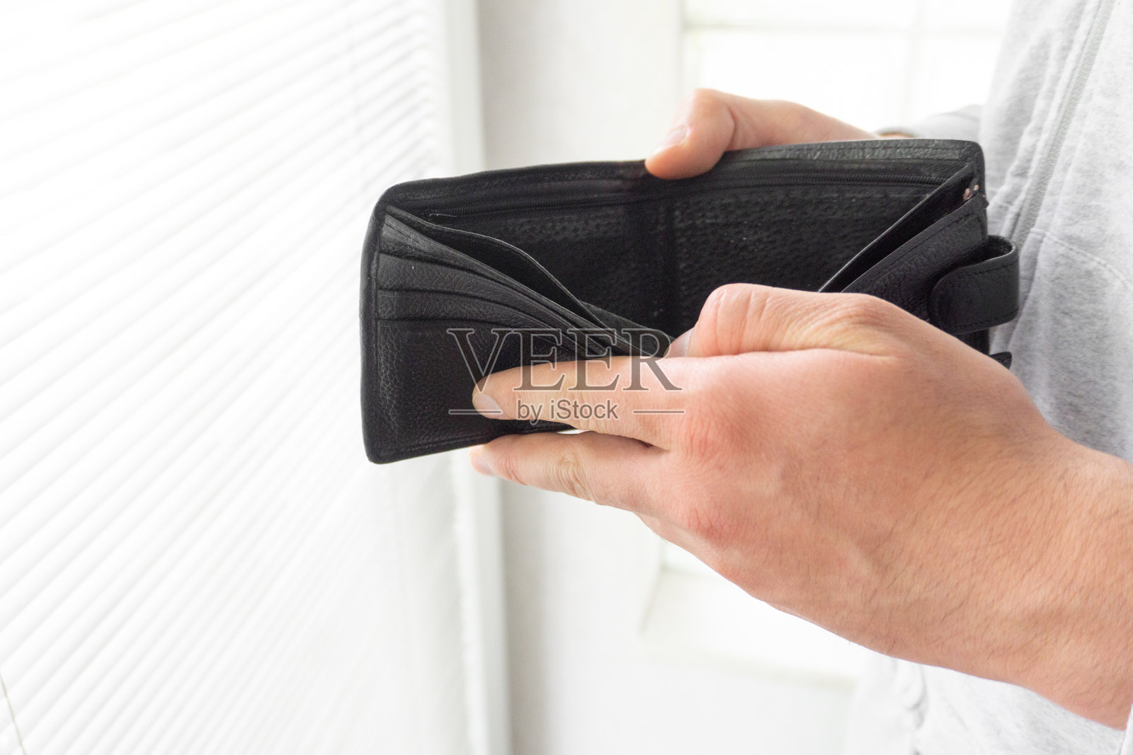 拿着空钱包的人把钱包收起来，穷人的手把空钱包打开照片摄影图片