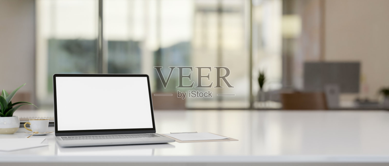 在现代办公室的桌子上，一台带有白色屏幕的笔记本电脑。照片摄影图片