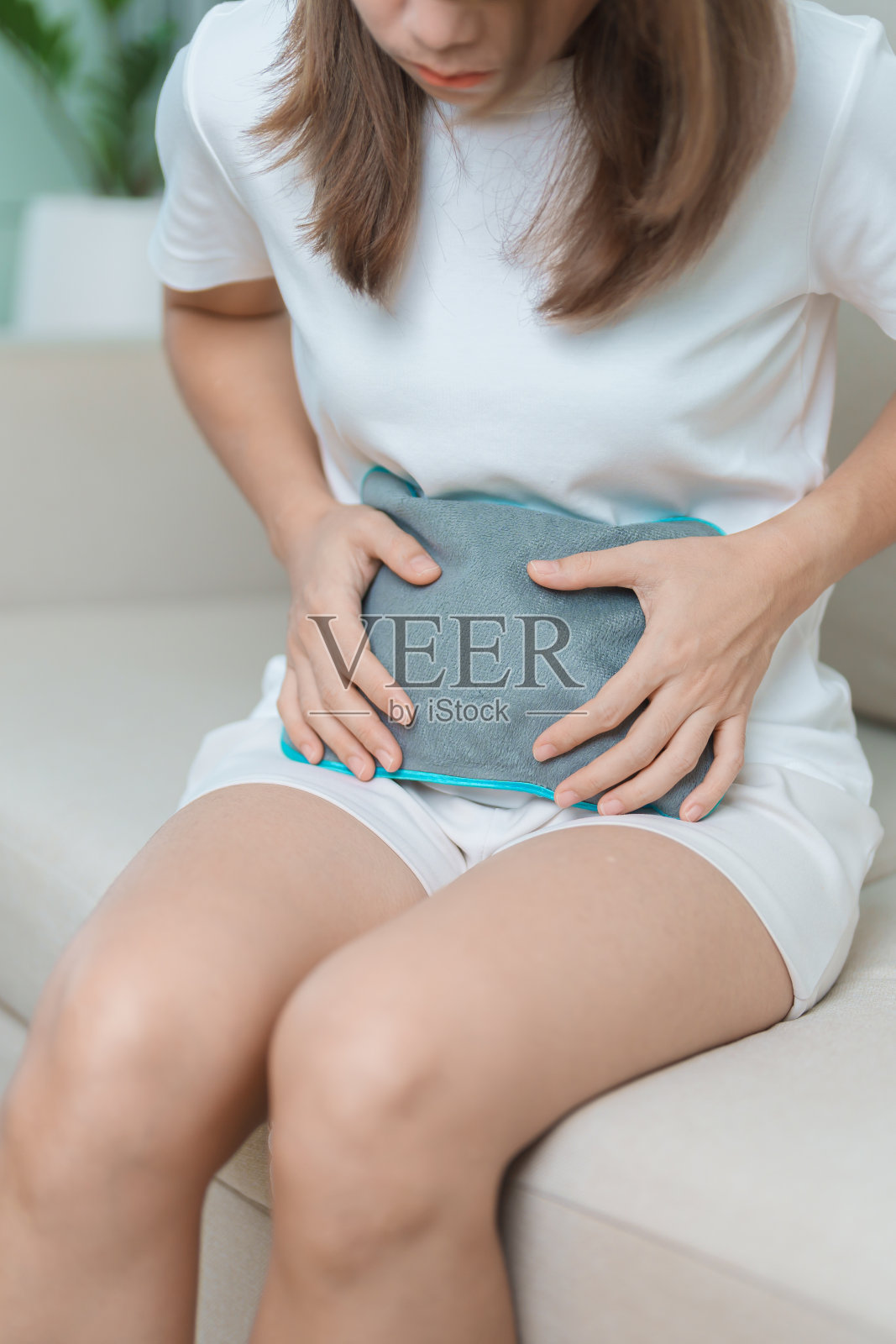 月经周期有月经周期和胃痛的概念。有腹部疼痛和经期疼痛的妇女用热水瓶，疾病妇女遭受经前疼痛和身体健康问题照片摄影图片