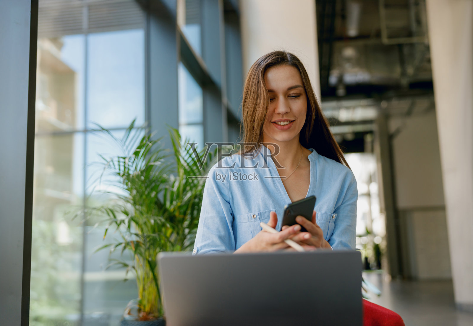 一名女子在现代办公环境中使用智能手机和笔记本电脑工作照片摄影图片