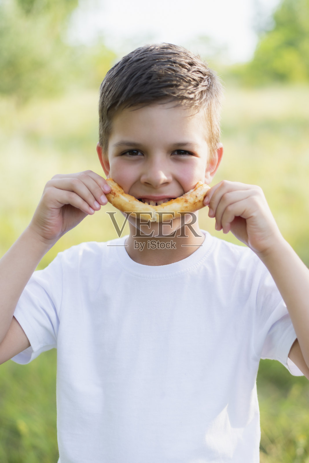 快乐的孩子用一块吃了一半的披萨的形式自然地微笑着照片摄影图片