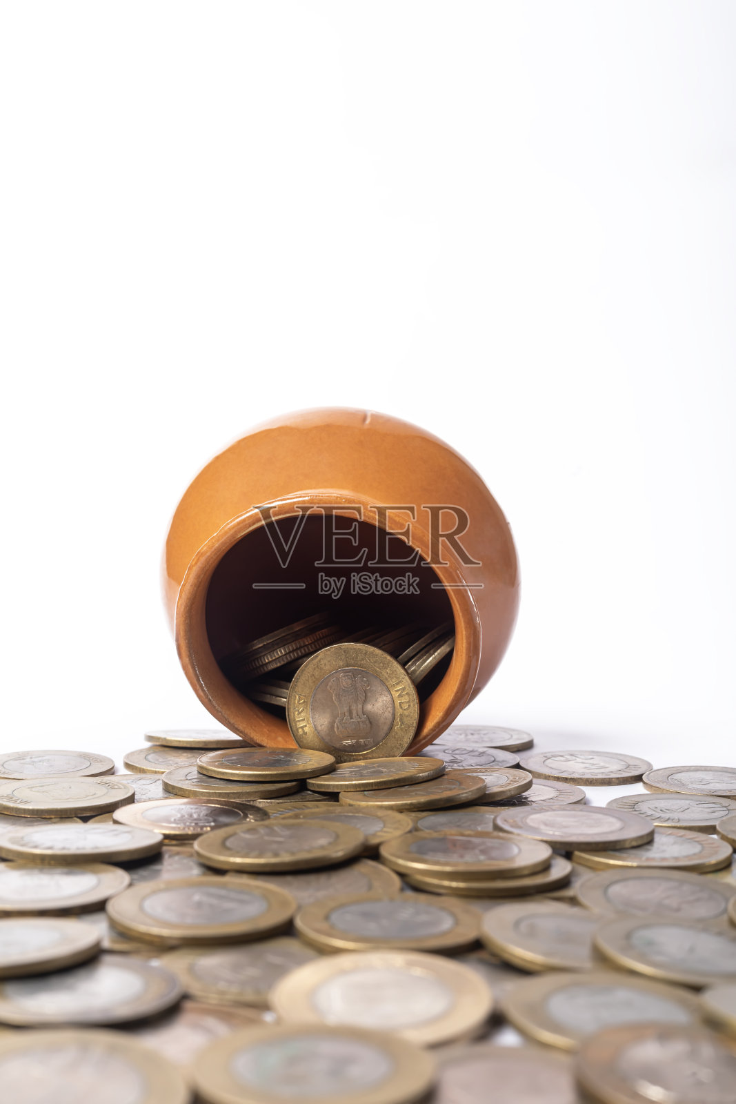 印度硬币从一个孤立在白色背景上的陶罐中溢出。照片摄影图片