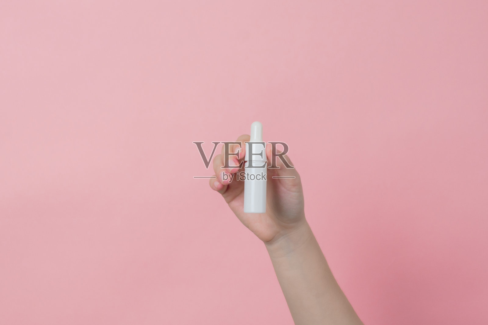 手持精华液玻璃白瓶(精油)与移液管。奢侈品化妆品广告照片摄影图片