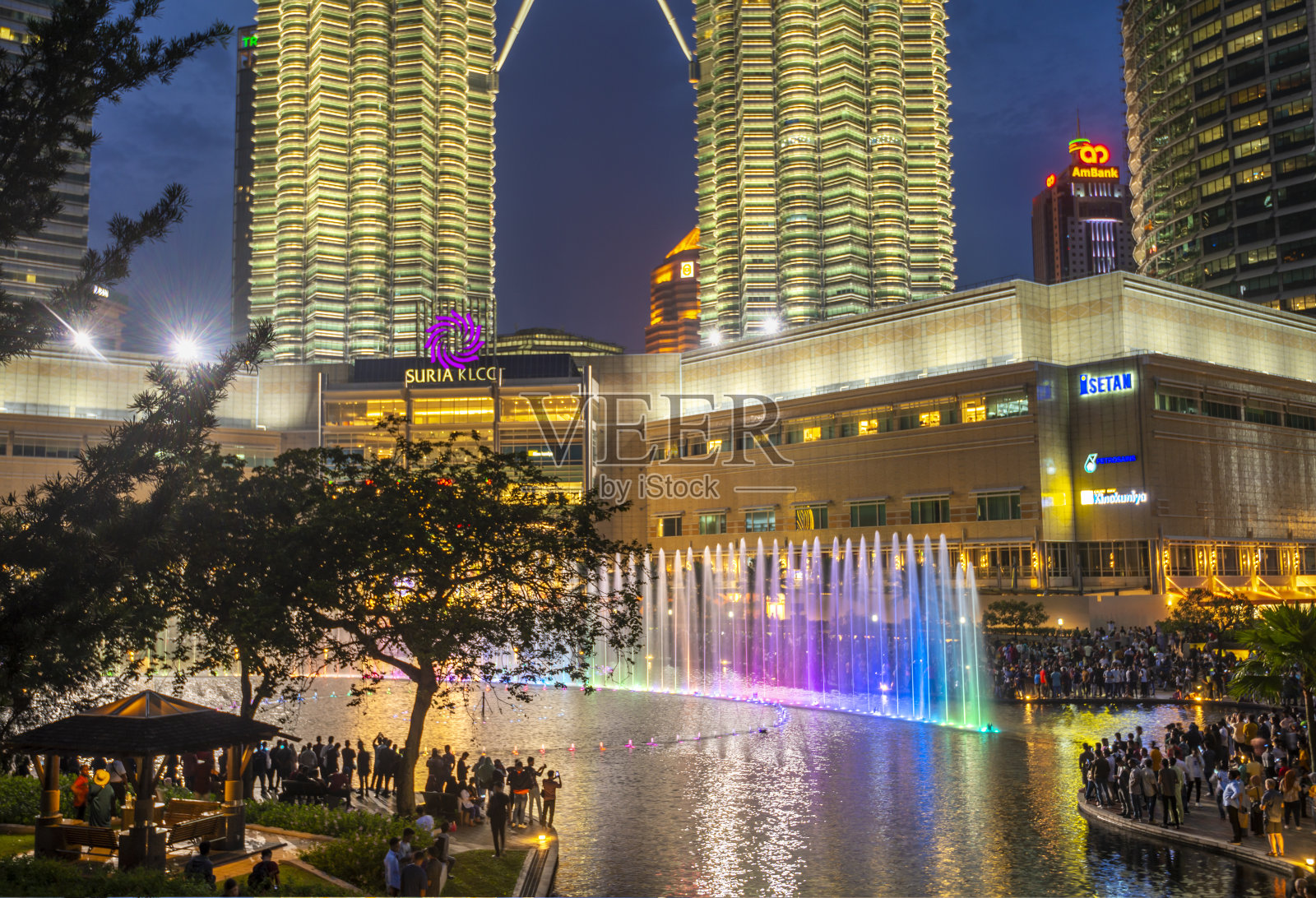 许多游客聚集在双子塔下，观看湖中交响乐表演。照片摄影图片