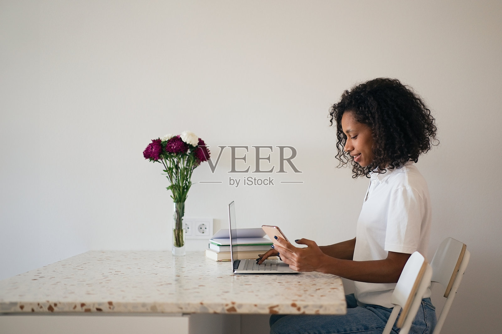 漂亮的年轻女子坐在厨房柜台前，喝着咖啡，用着笔记本电脑照片摄影图片