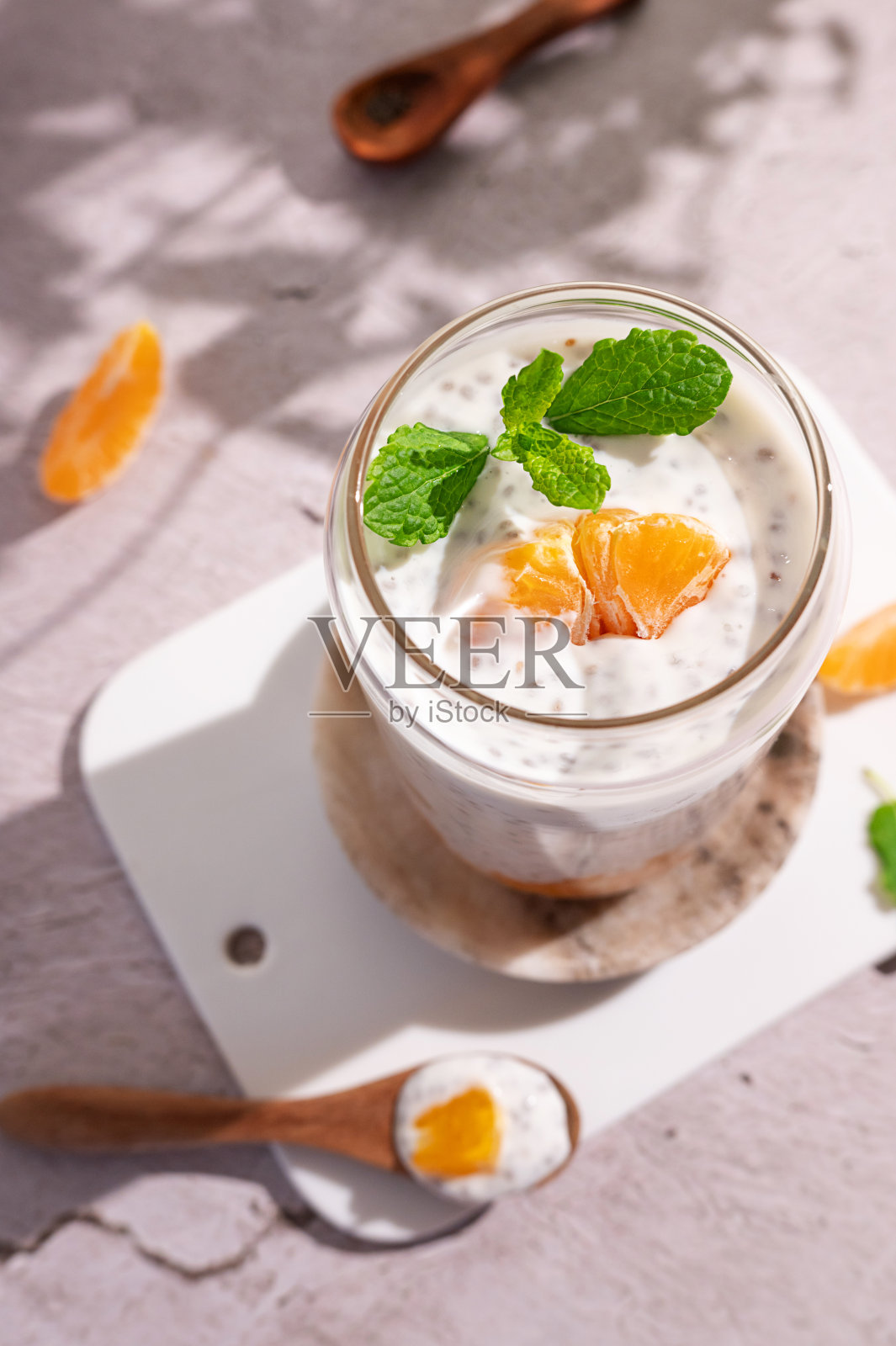 一杯和一勺酸奶和一杯由纯素牛奶和种子制成的奇亚布丁。照片摄影图片