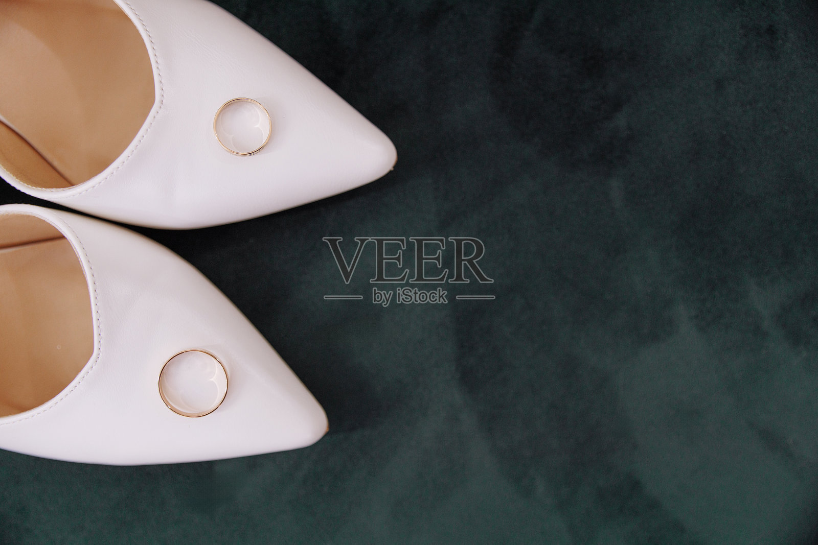 白色的鞋子和绿色背景上的金戒指照片摄影图片