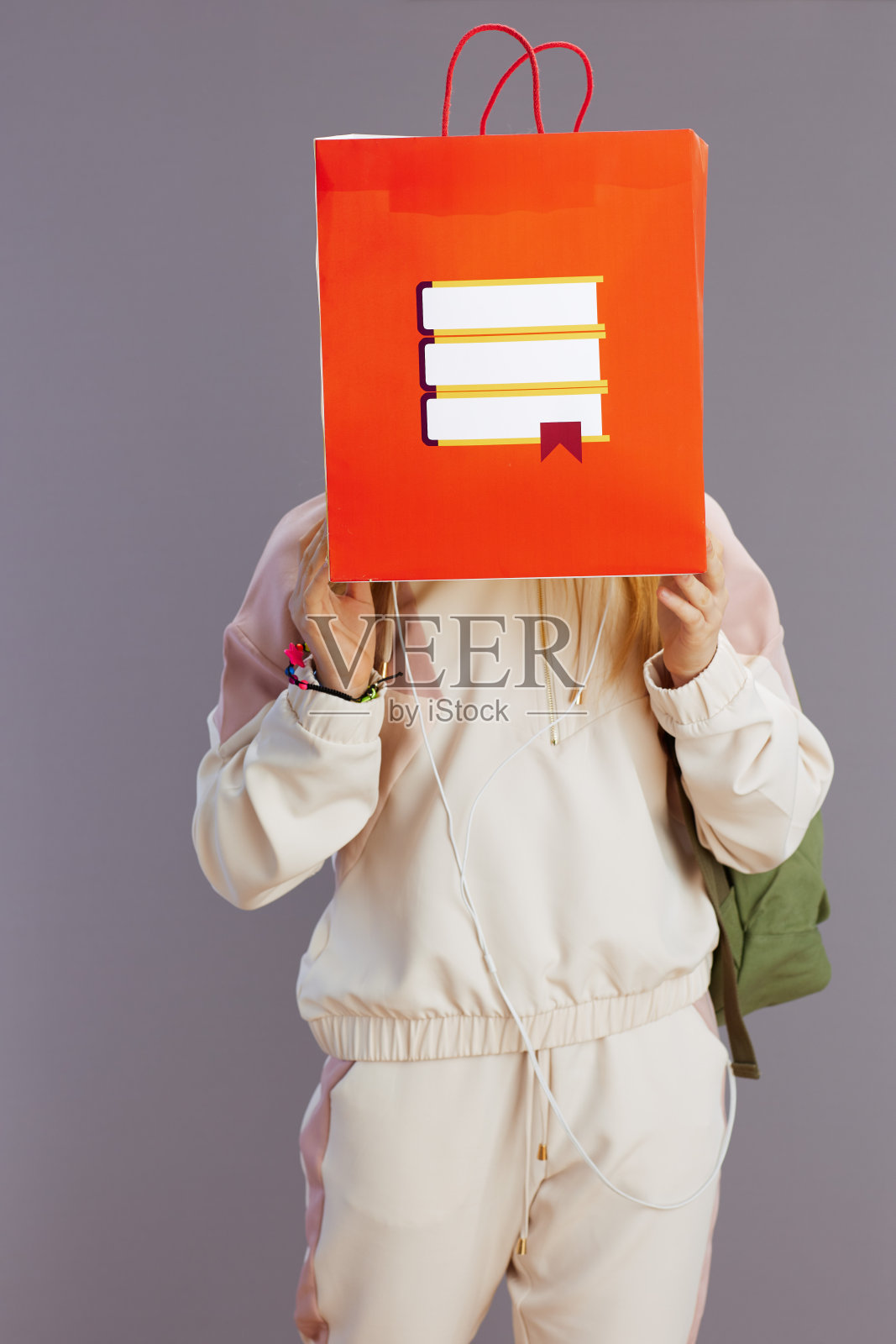 穿着米色运动服背着双肩包的时髦少女照片摄影图片