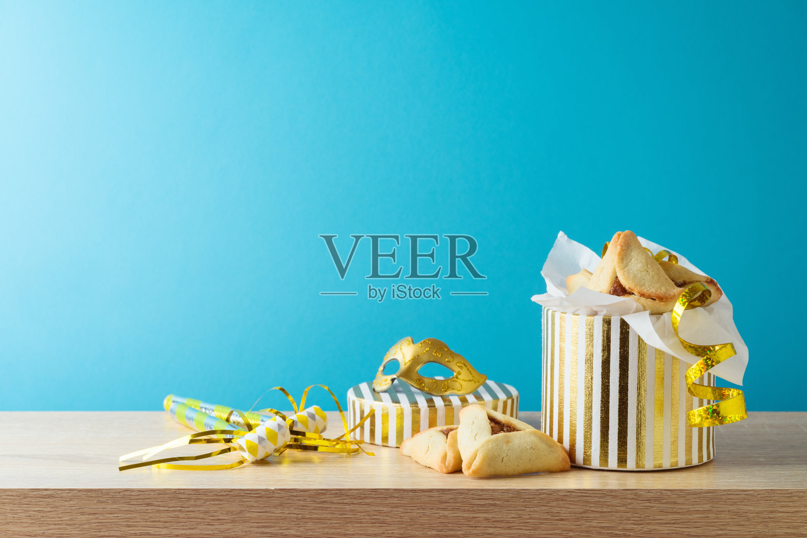 犹太节日普里姆概念，蓝色背景的木制桌子上有哈曼塔什饼和狂欢节面具照片摄影图片