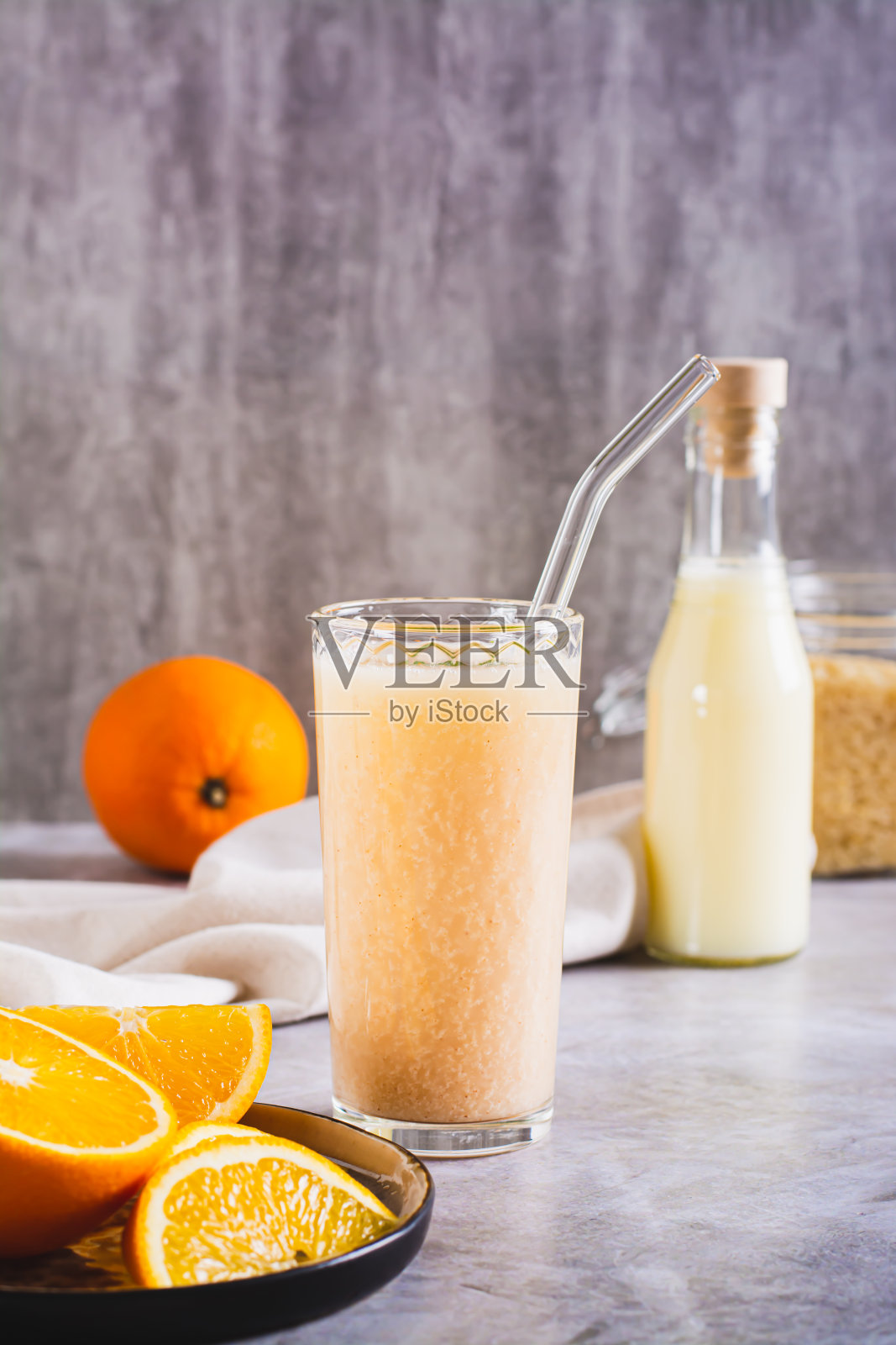 用米浆和橙汁做成的素食冰沙放在桌子上的玻璃杯里垂直观看照片摄影图片