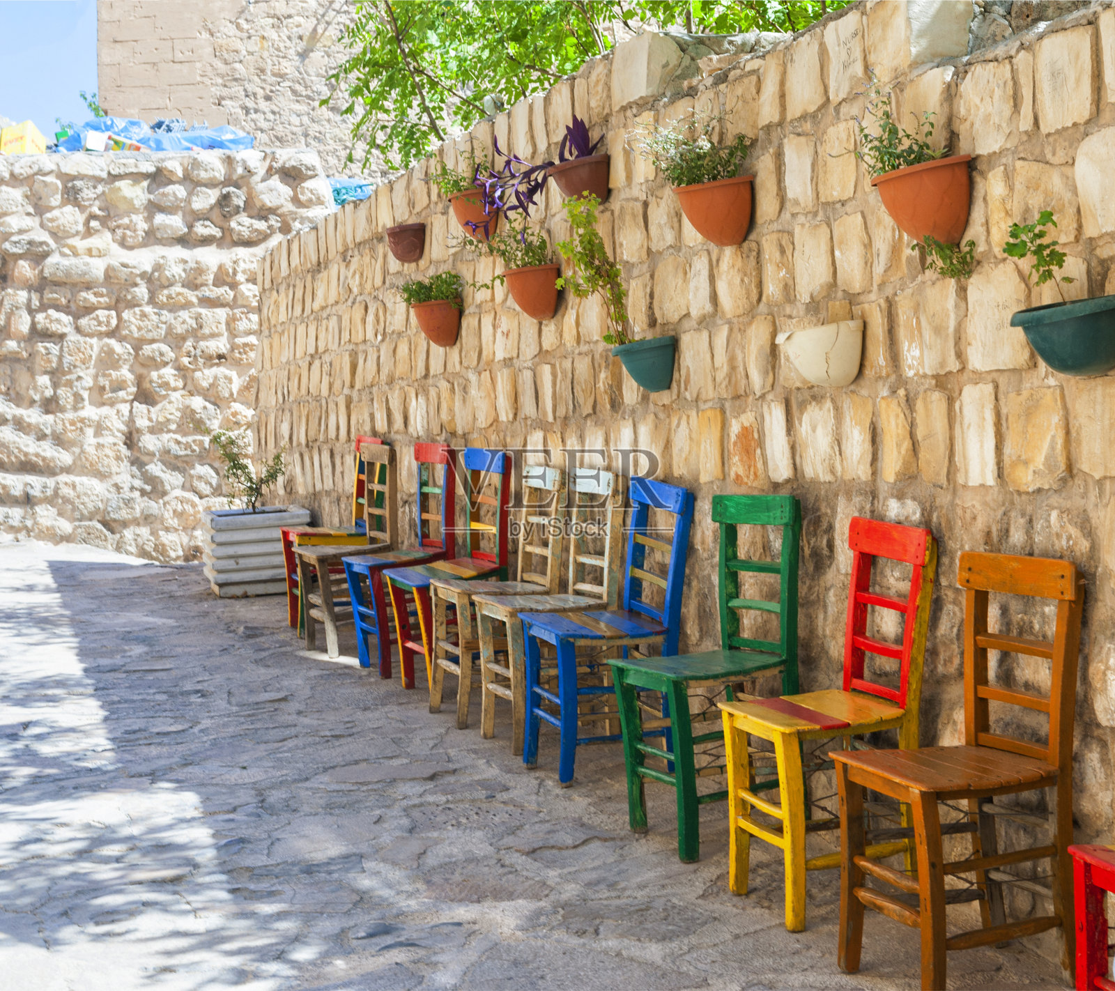 土耳其马尔丁街道上的一堵旧墙前，五颜六色的手工木椅照片摄影图片