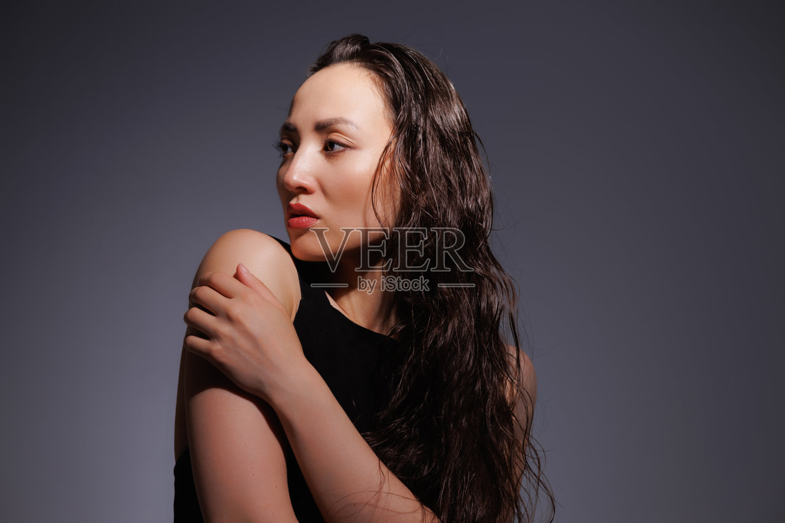 时尚的亚洲女人，红唇，湿发，在灰色的背景上孤立地摆姿势照片摄影图片