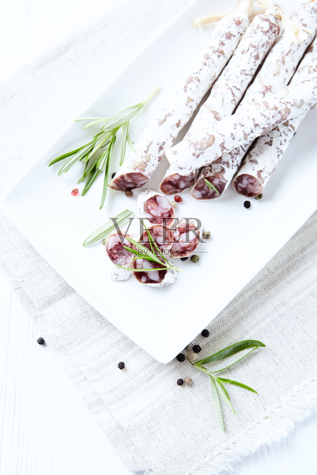 切片的法国腊肠配上新鲜的迷迭香，白色背景。副本的空间。照片摄影图片