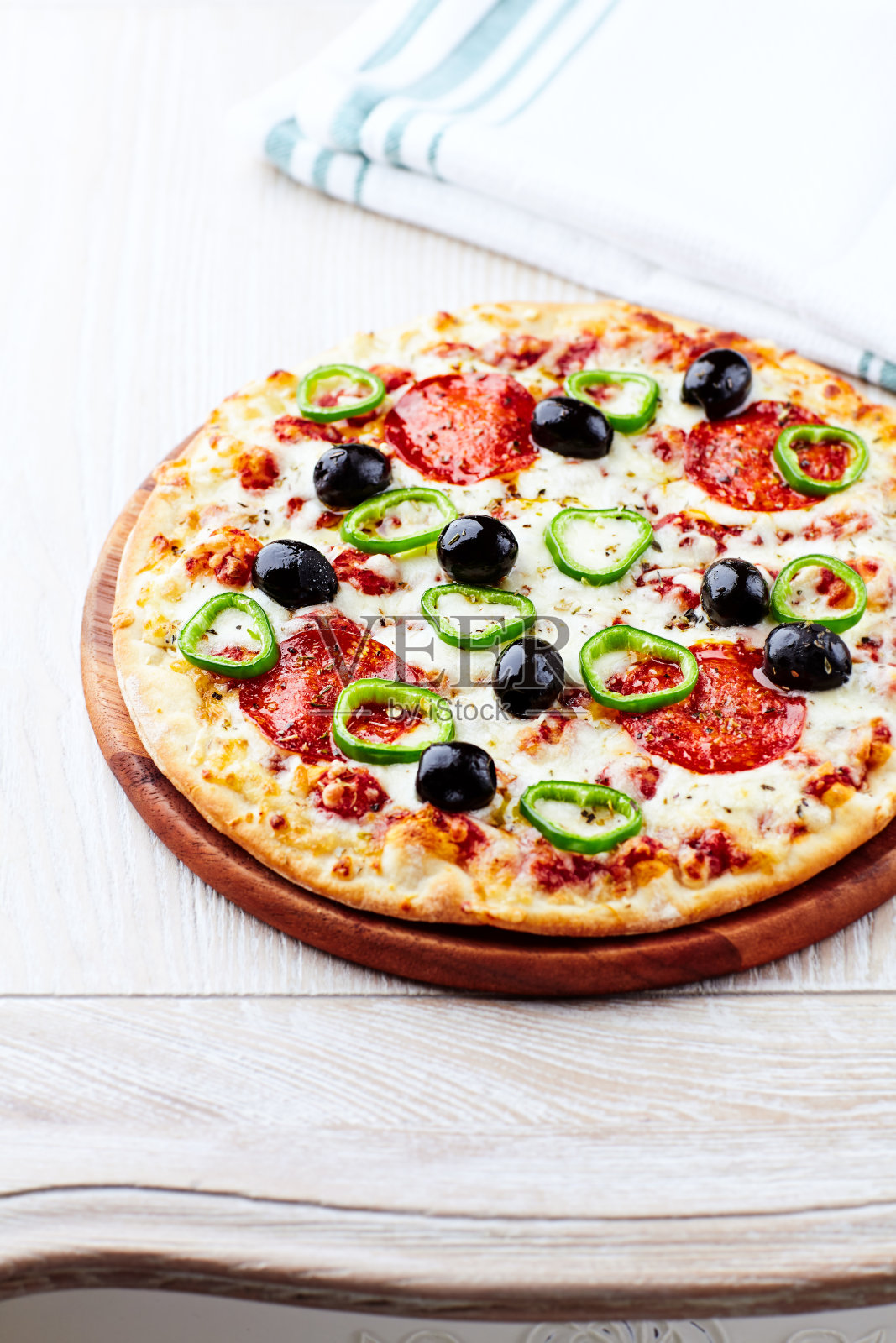 披萨配意大利腊肠，墨西哥胡椒和黑橄榄。家常菜。一个美味和丰盛的一餐的概念。关闭了。照片摄影图片