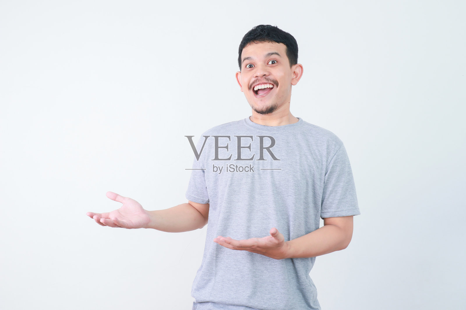 快乐的亚洲人正用手指着空的地方递东西。照片摄影图片