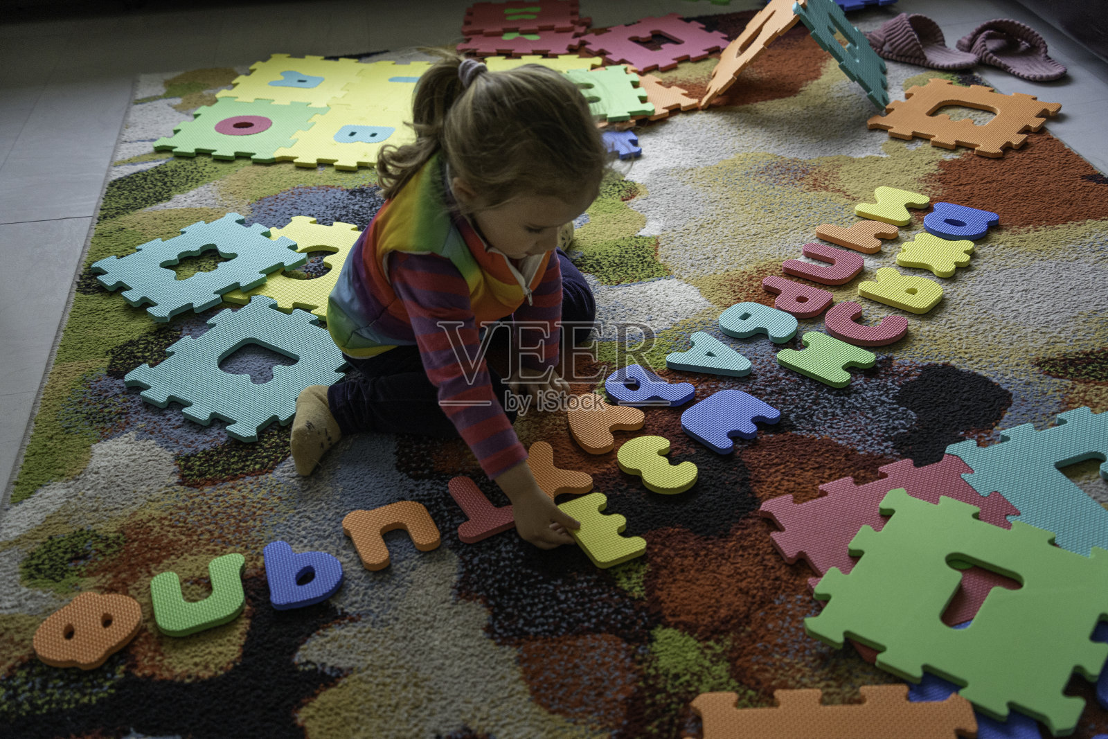 儿童早期发展：女孩在家玩字母玩具垫照片摄影图片