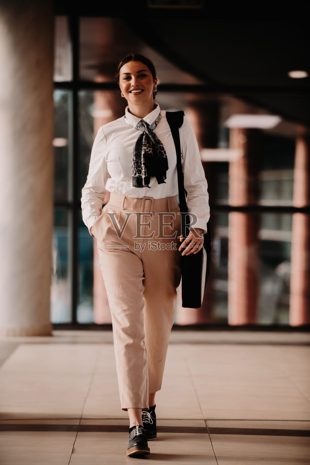 被授权的拉丁女商人在现代办公室自信地大步迈进。照片摄影图片